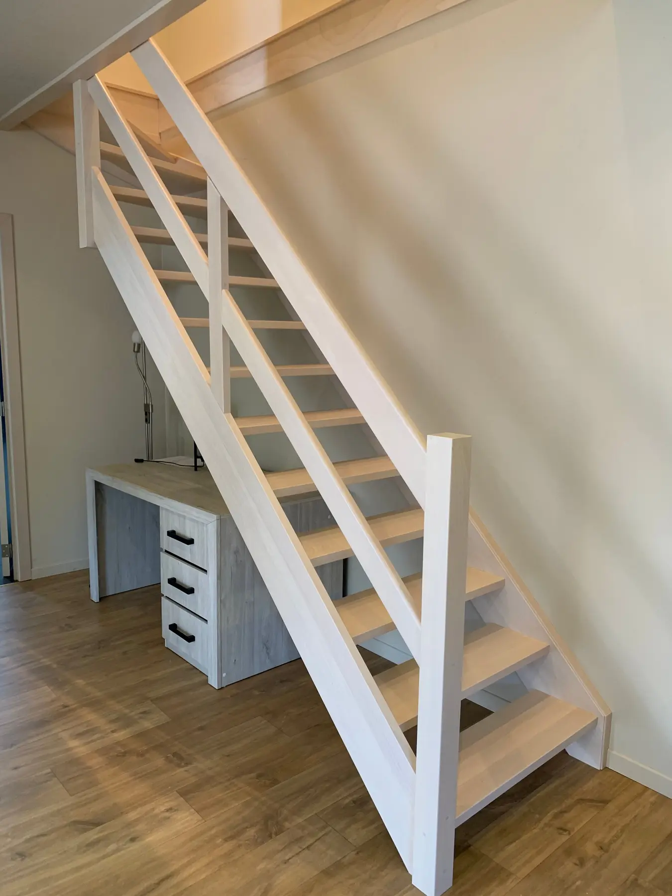 Wit geschilderde houten trap met leuning en eiken treden