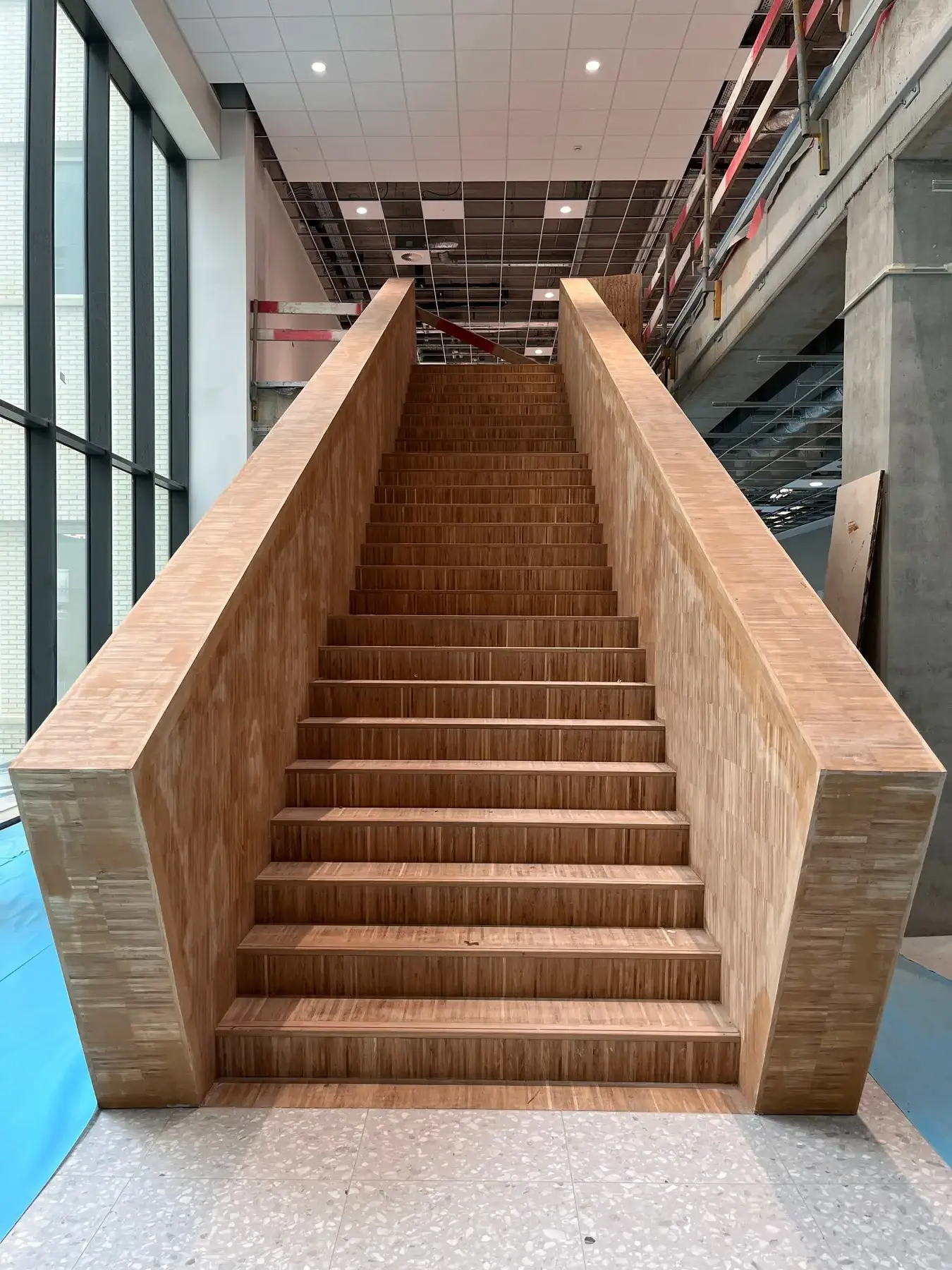 Brede houten trap in een groot gebouw in afwerking