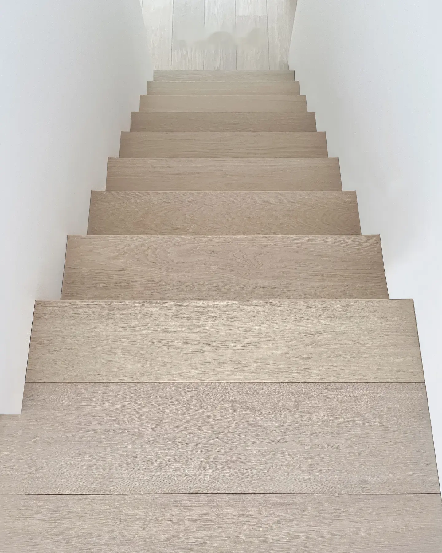 Rechte trap bekleed met lichte eiken treden en stootborden