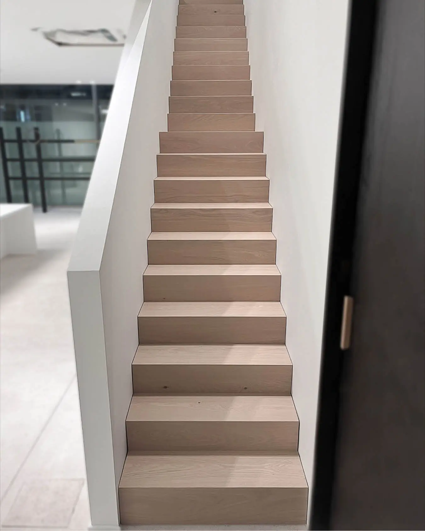 Straight oak staircase in a bright hallway